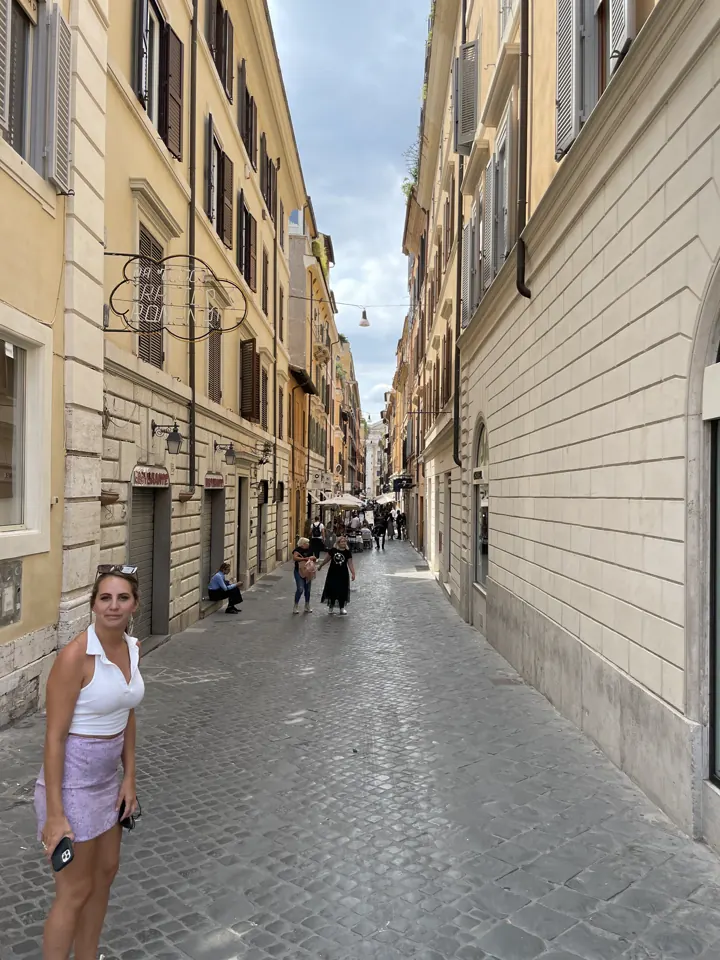 A woman walking down a quiet street lined with ochre buildings