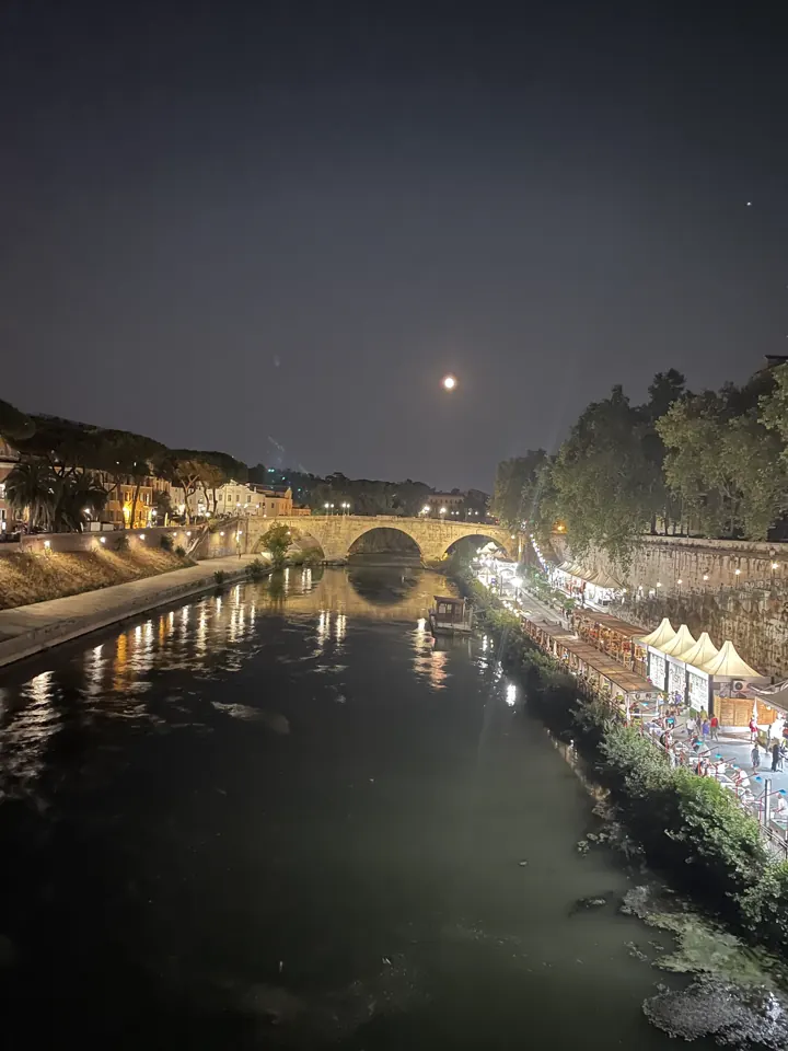The Tiber River at night reflecting a lit bridge