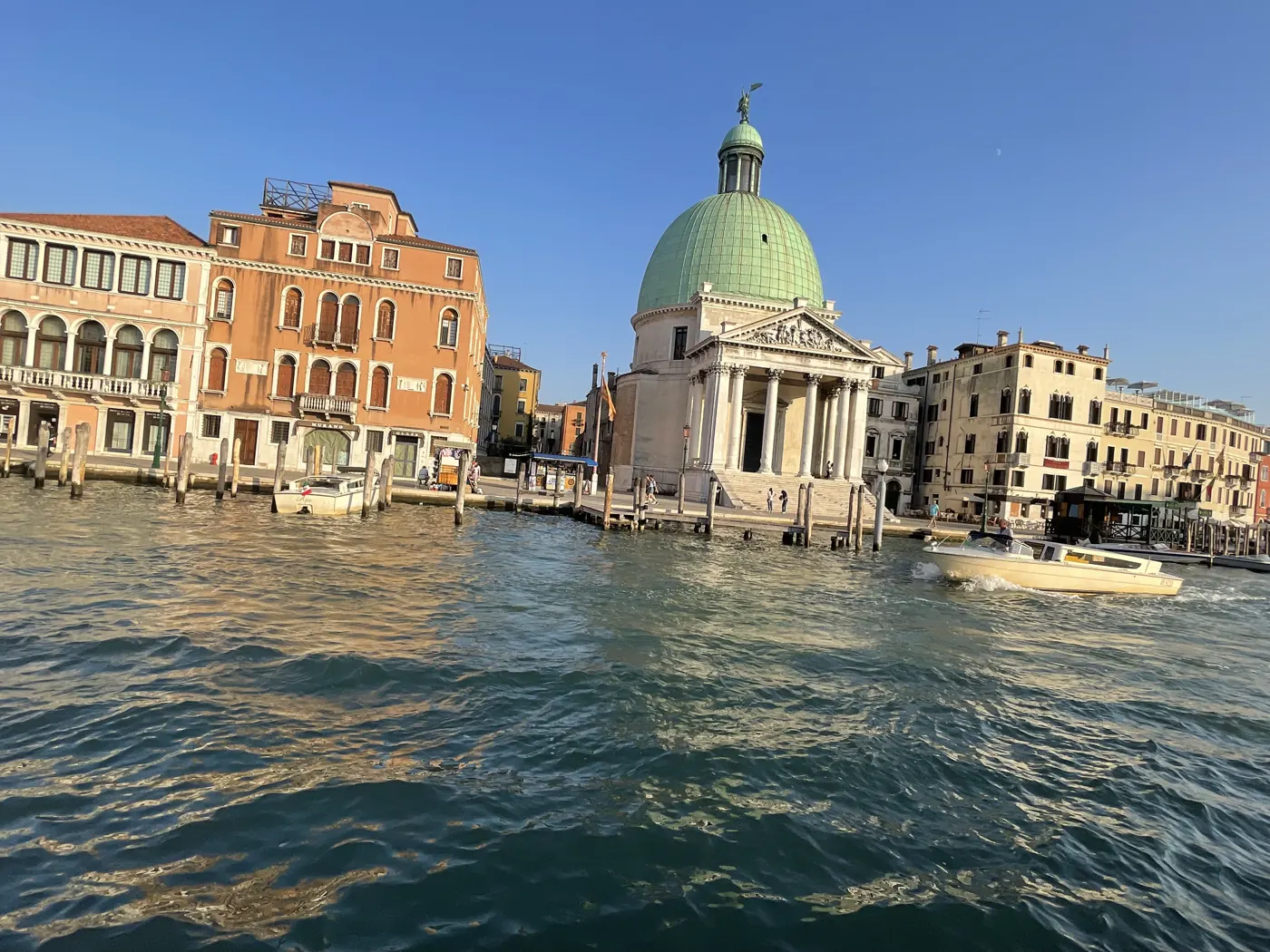 The Grand Canal with a green-domed church and pastel palazzos under a blue sky