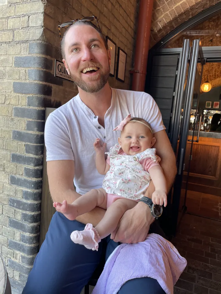 Colin laughing with Andi on his lap at a London restaurant