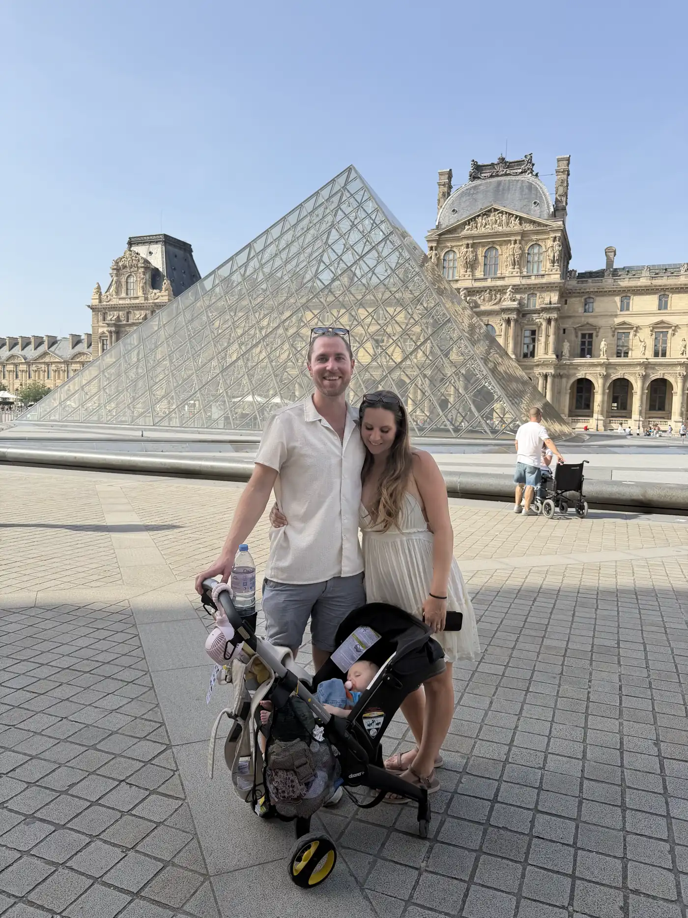 Colin pushing the stroller past the Louvre pyramid