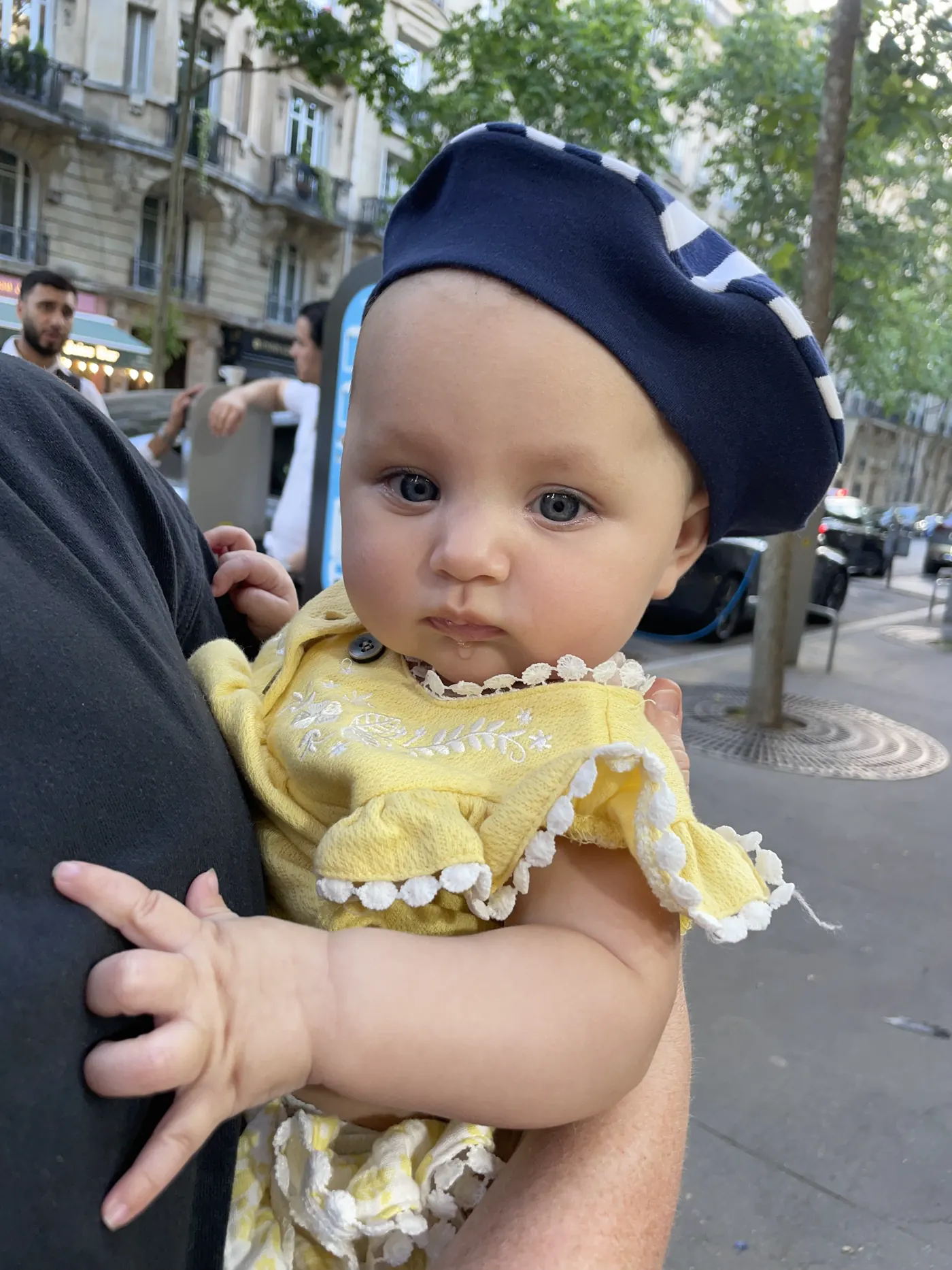 Andi in a navy beret and yellow outfit on a Paris street