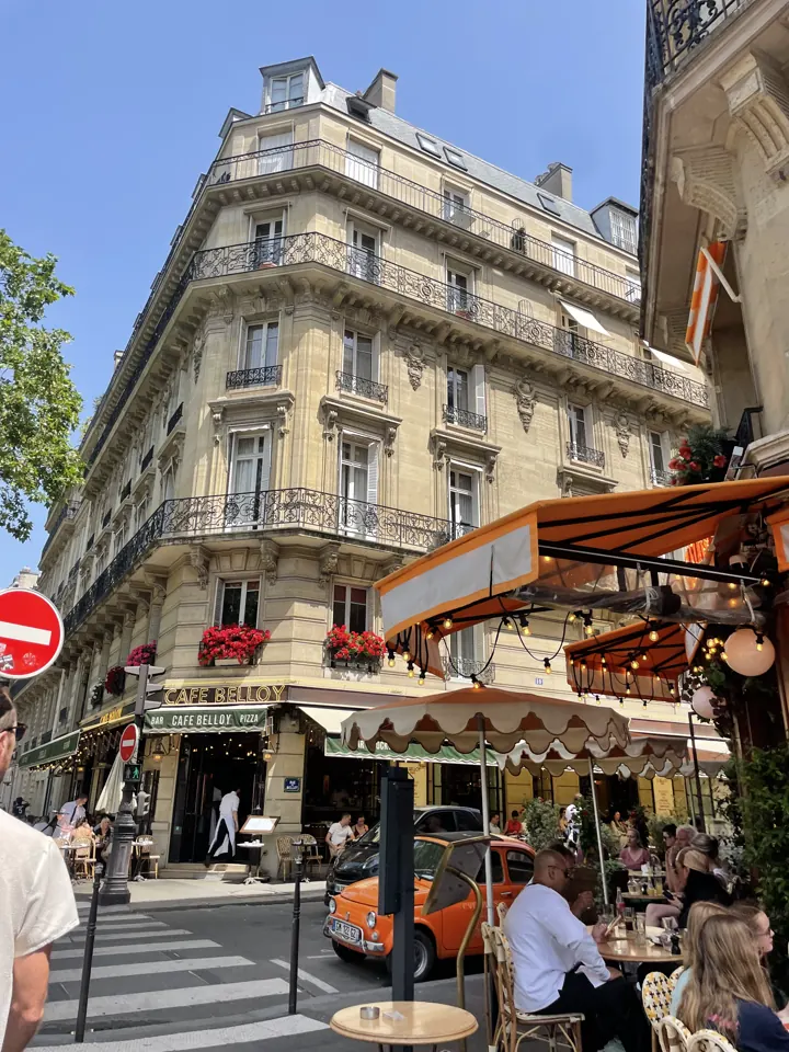 A Paris corner café with red awnings and outdoor tables