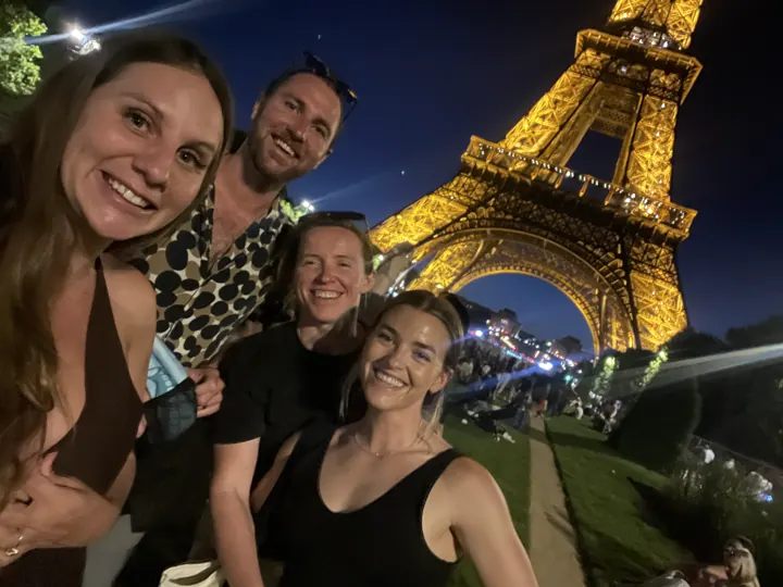 Friends together with the Eiffel Tower sparkling at night