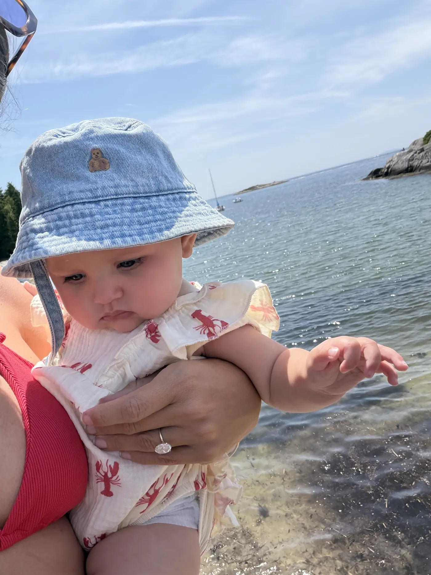 Baby Andi in a blue bucket hat by the water in Boothbay Harbor