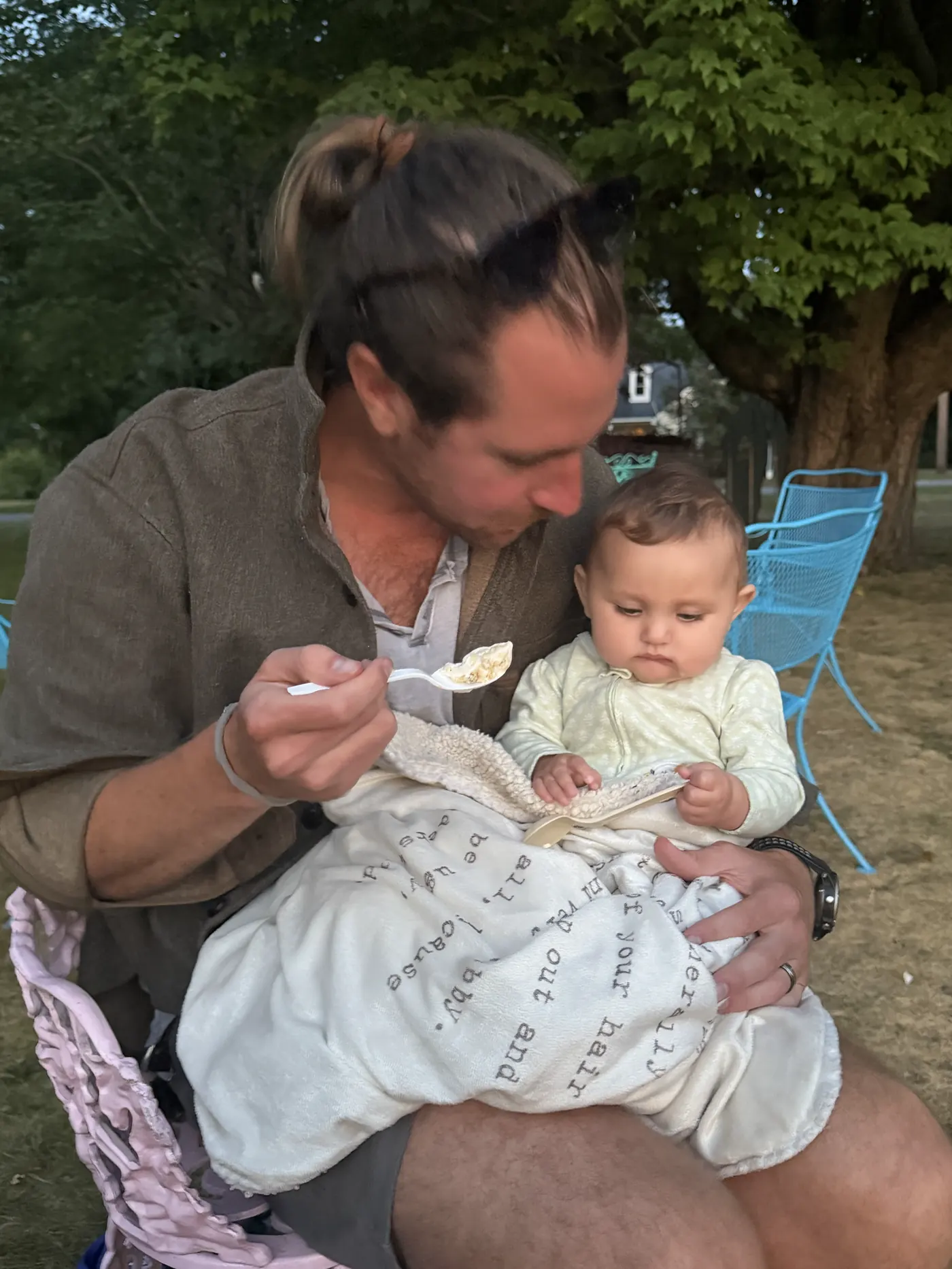 Colin feeding baby Andi on a picnic blanket