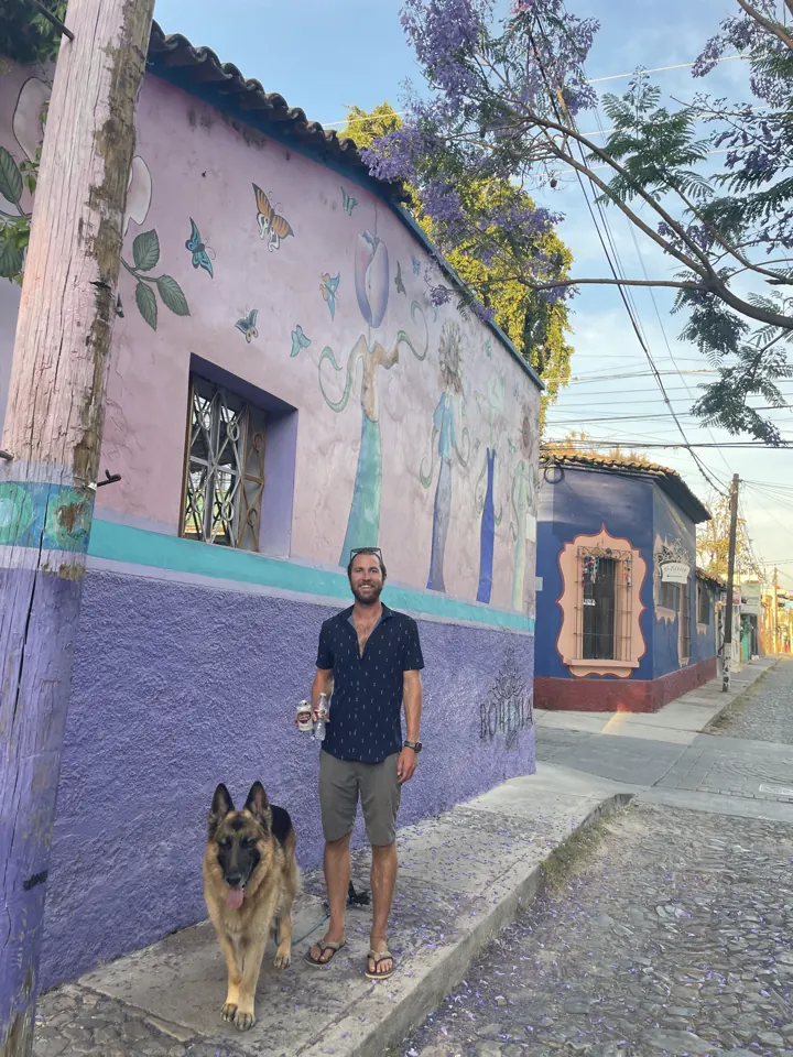 Colin and Jack, our German Shepherd, standing by a purple painted building on a cobblestone street
