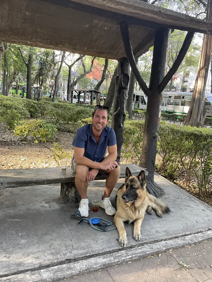 Colin sitting on a park bench with Jack, our German Shepherd, in Mexico City
