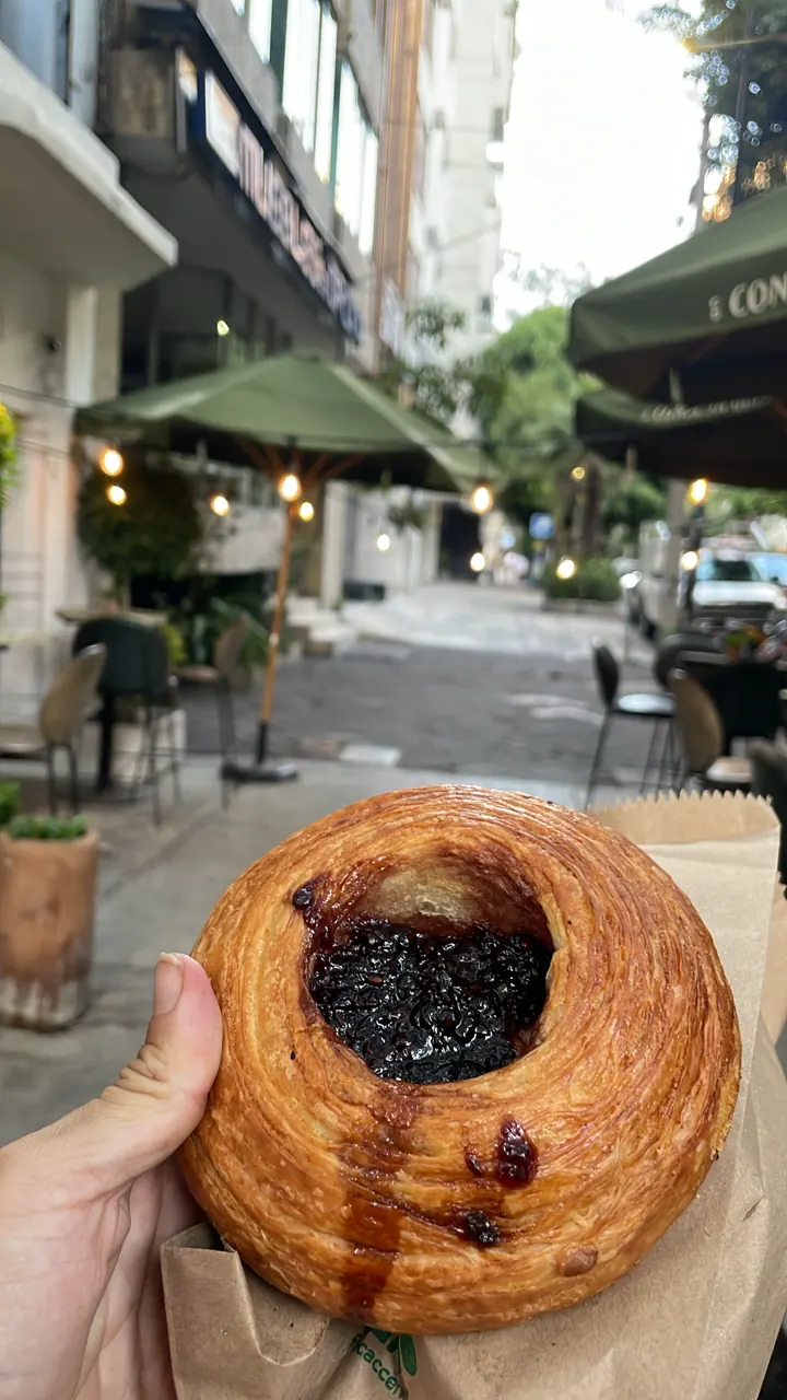 Hand holding a glazed pastry on a Mexico City street