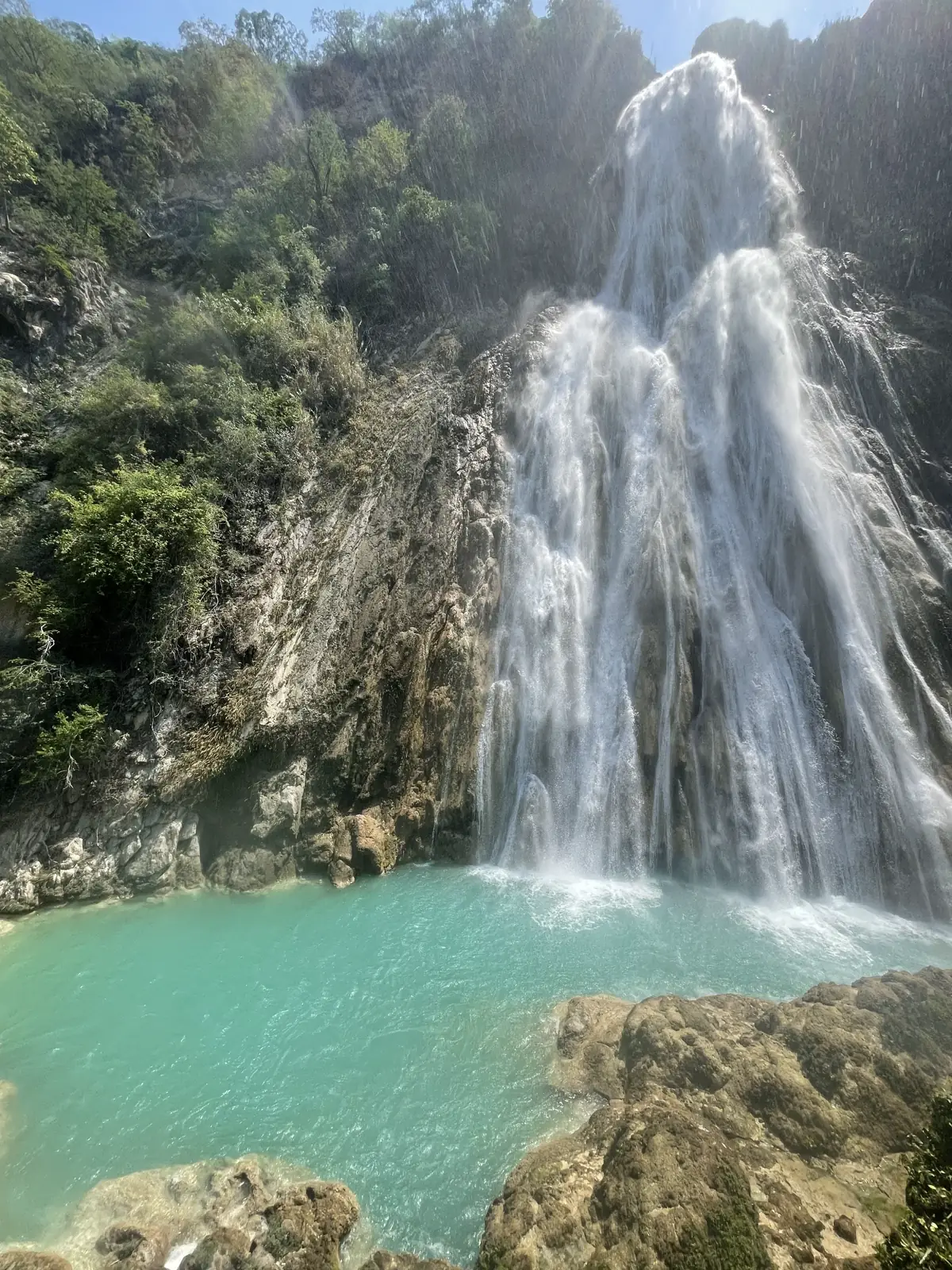 Tall waterfall pouring into a turquoise pool surrounded by jungle