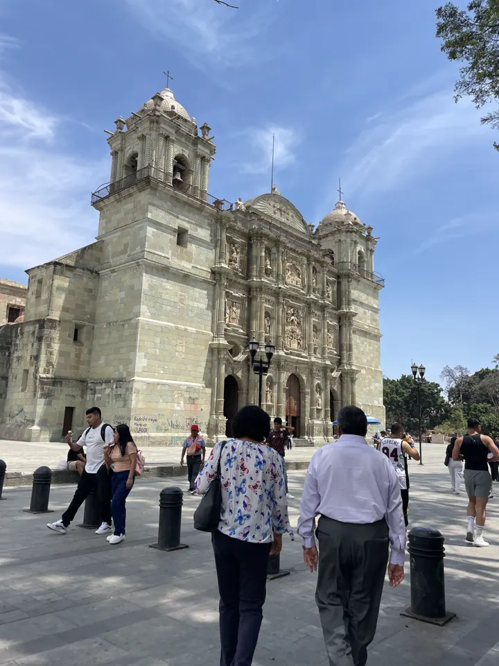 Stone facade of the Santo Domingo church in Oaxaca with people in the plaza