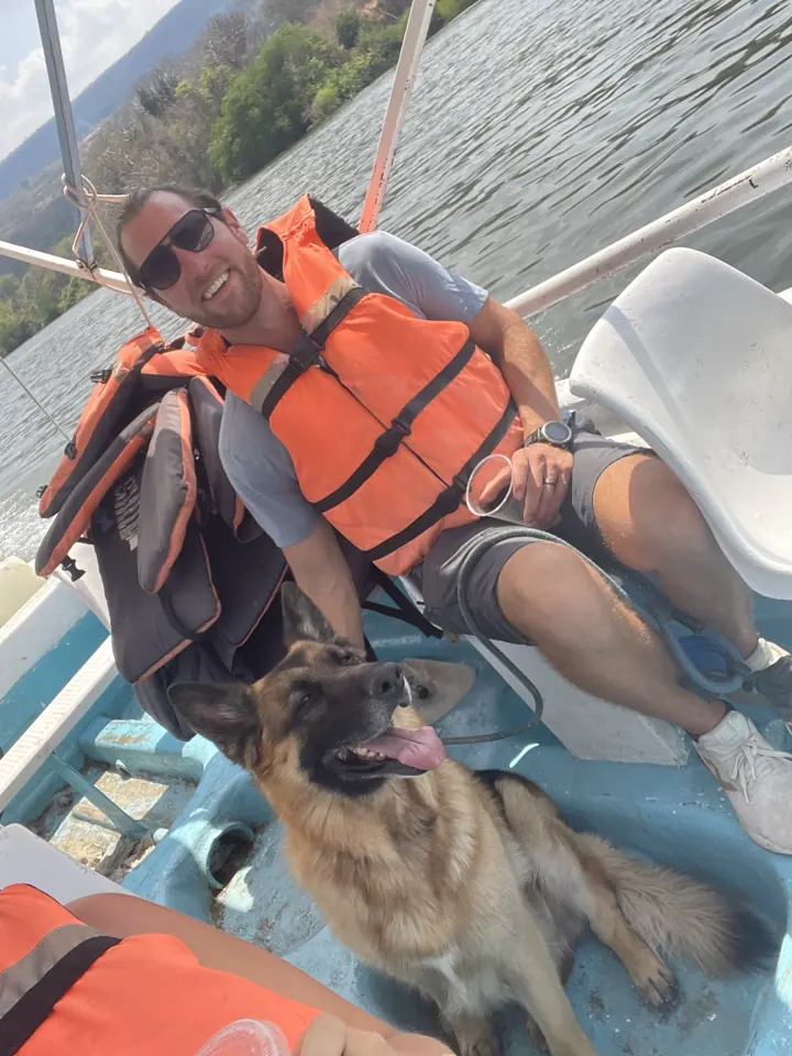 Colin in an orange life jacket on a boat with Jack, our German Shepherd