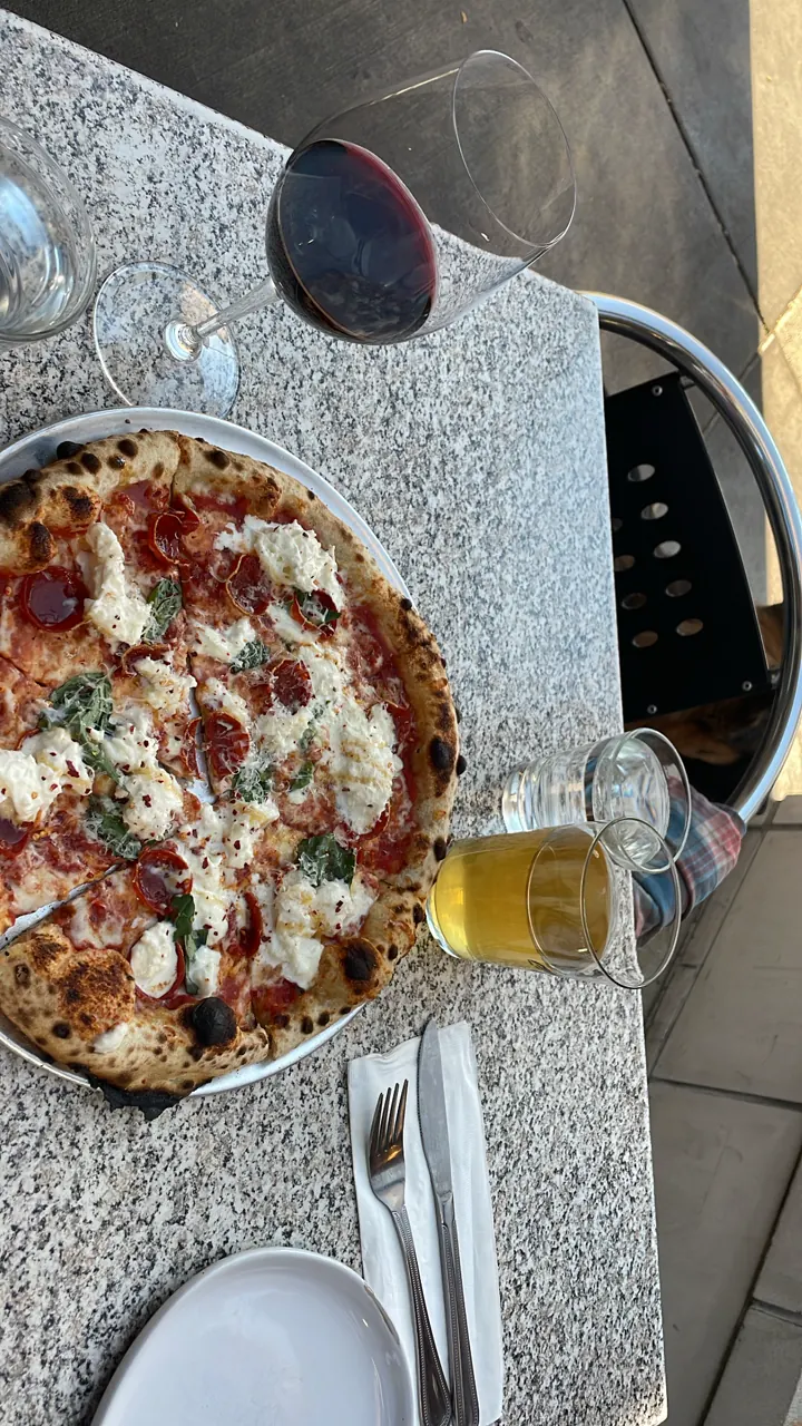 A pizza topped with pepperoni next to a glass of beer on a restaurant table