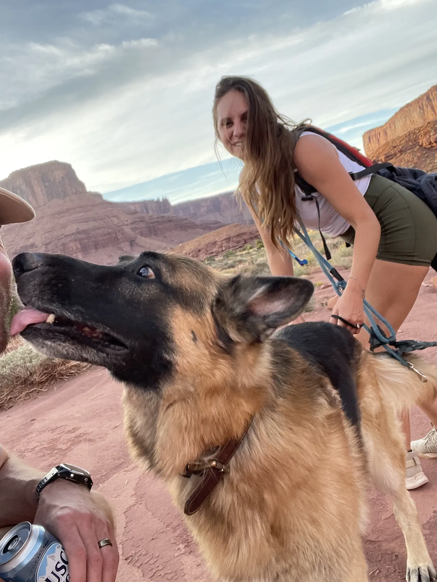 Jack, our German Shepherd, panting happily next to Angela on a red rock trail