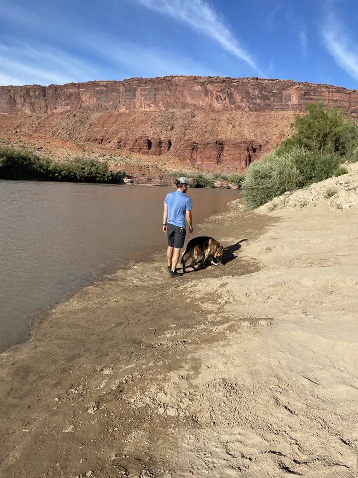 Colin and Jack, our German Shepherd, on a sandy riverbank below red cliffs