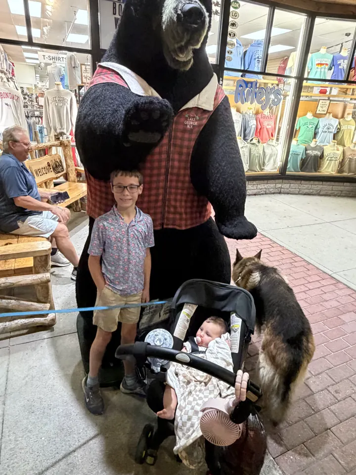 Colin with the stroller and Jack next to a big bear statue in Lake George village