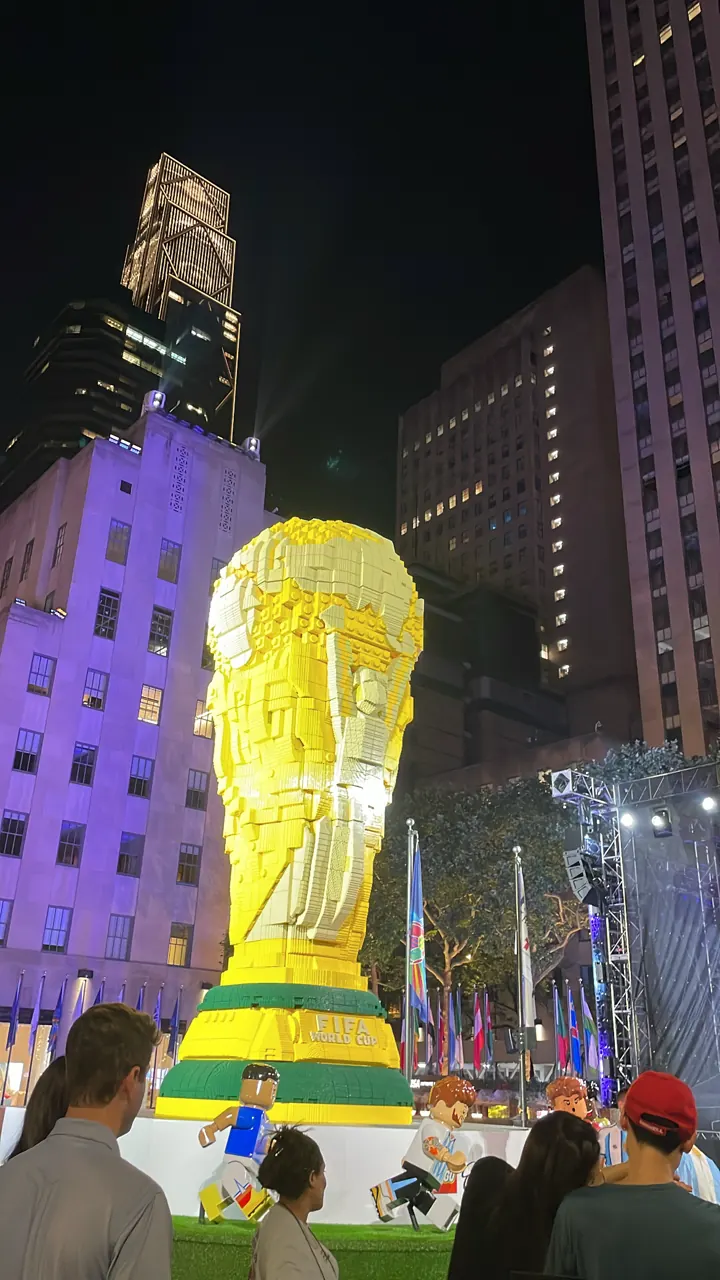 A giant World Cup trophy display lit up at night in New York