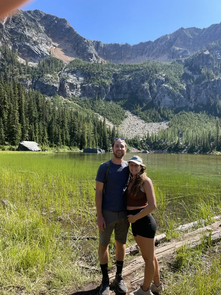 Colin and Angela hugging in a meadow below rugged mountains