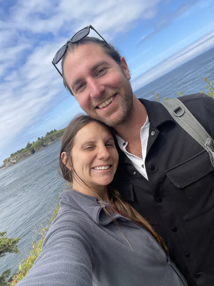 Colin and Angela smiling in a selfie by the water