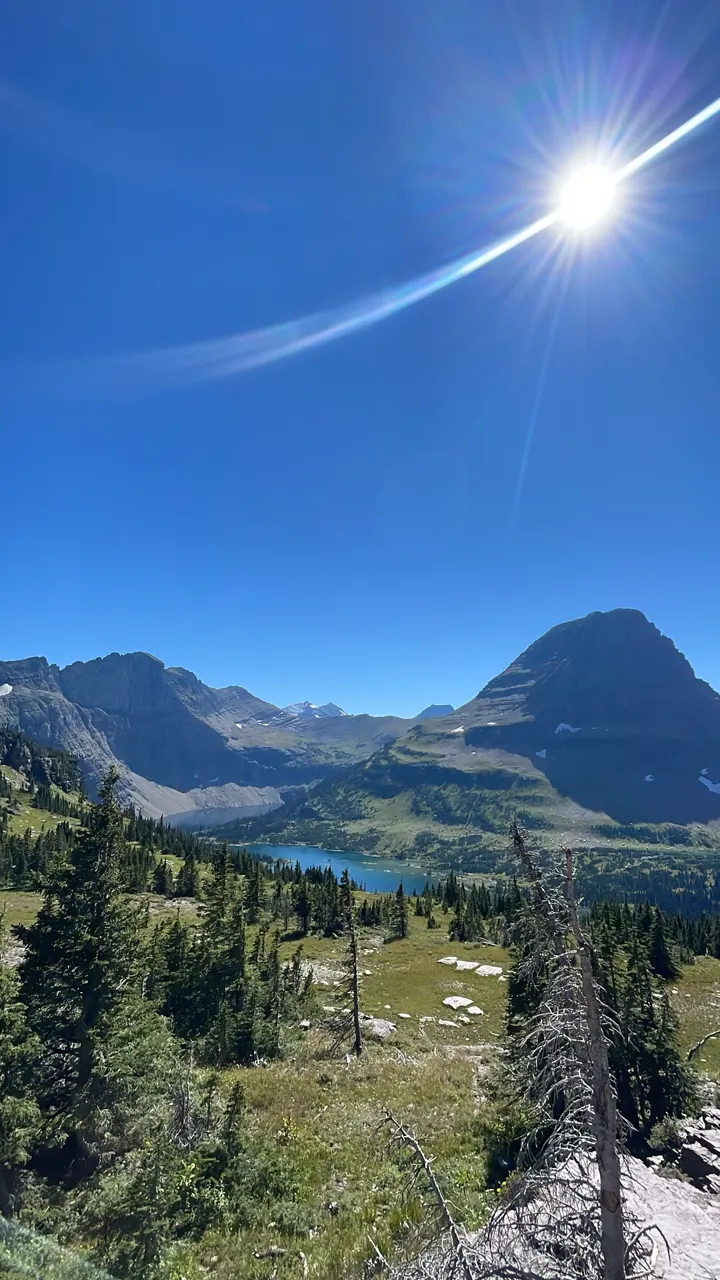 Valley with a distant lake and peaks, sun in the sky