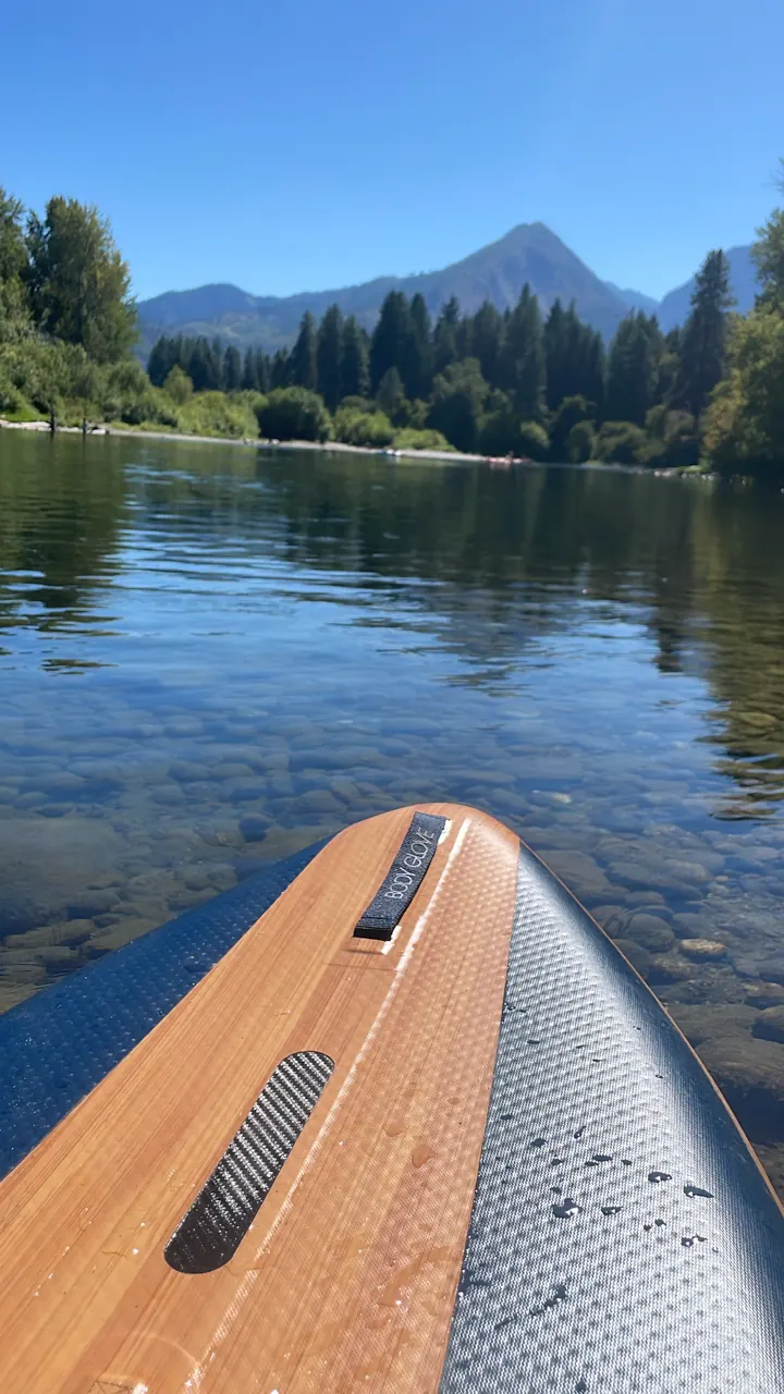 Wooden paddleboard nose on a calm blue lake with peaks ahead