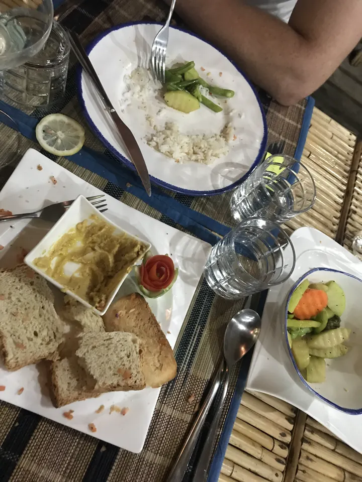 A breakfast spread of toast, rice, pickled vegetables and sauces on a woven table