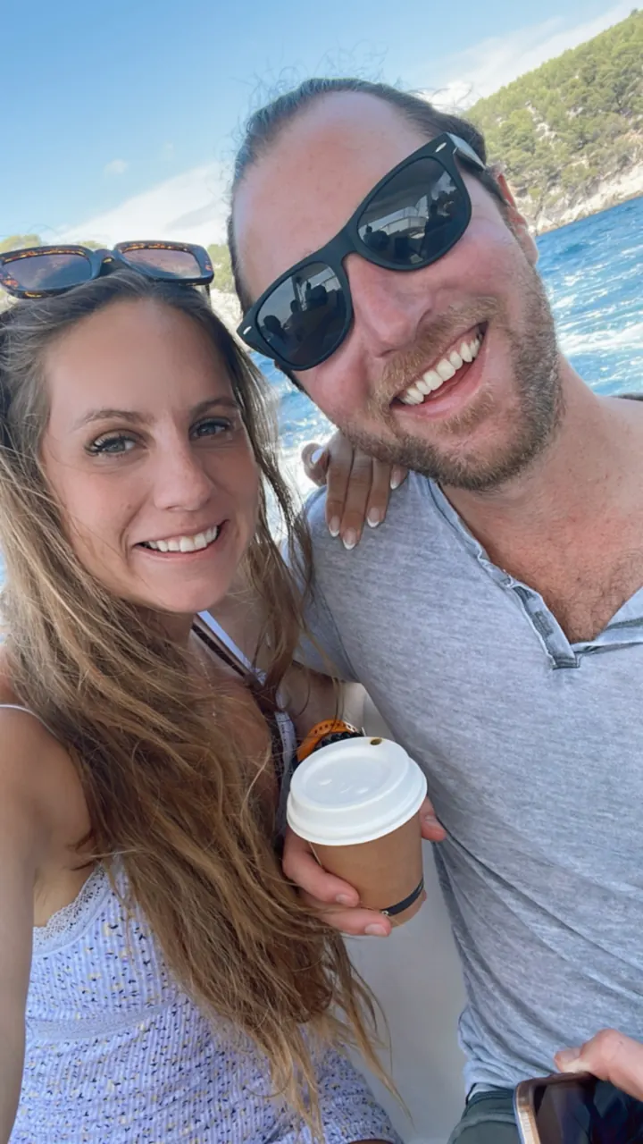A couple taking a selfie with coffee and the sea behind