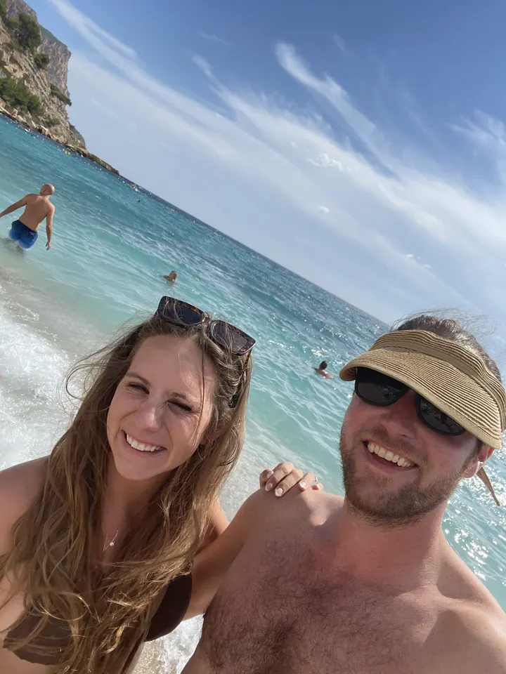 A couple taking a selfie on a beach with the sea behind