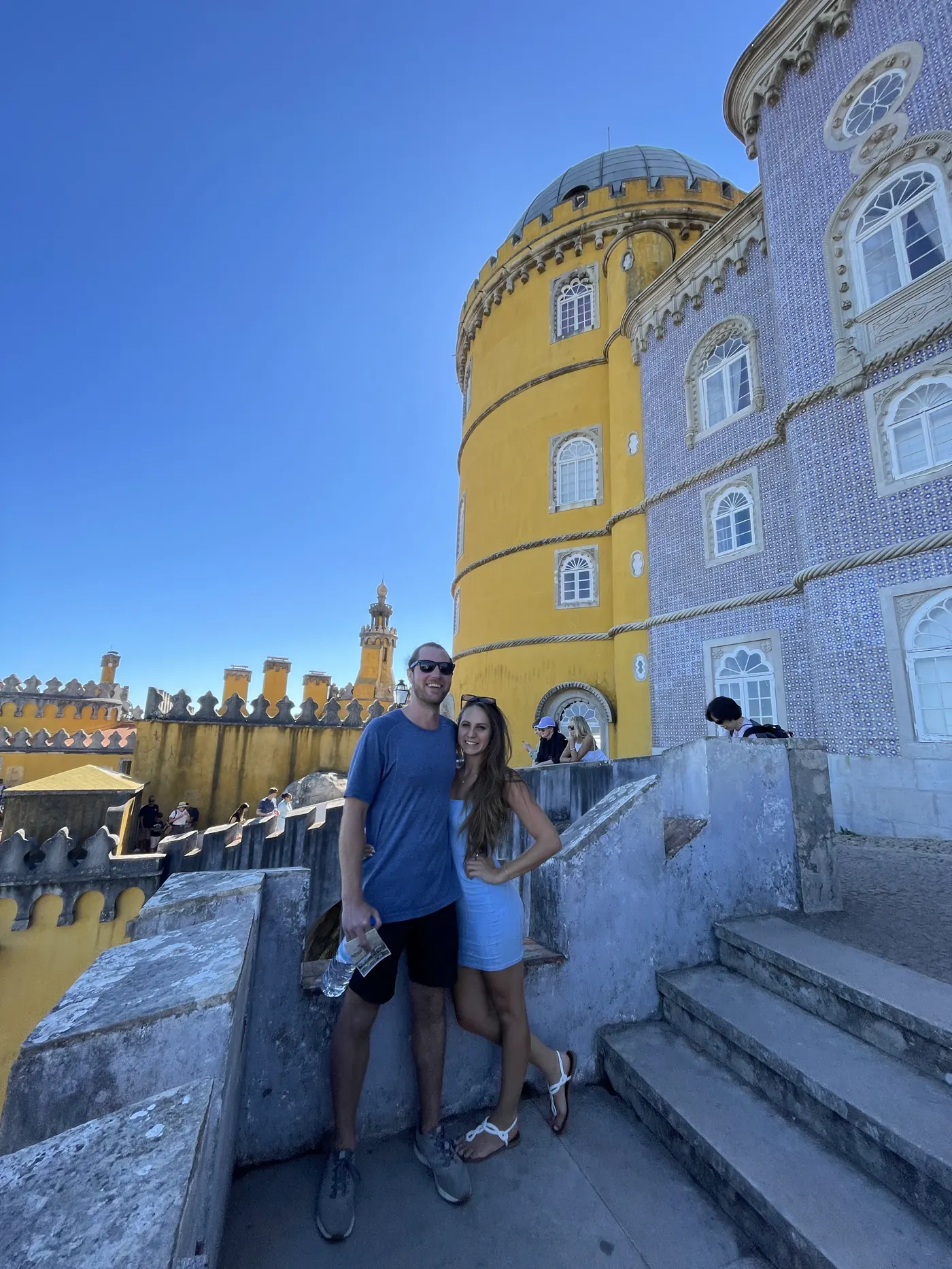 A couple on the terrace of Pena Palace with its yellow tower behind