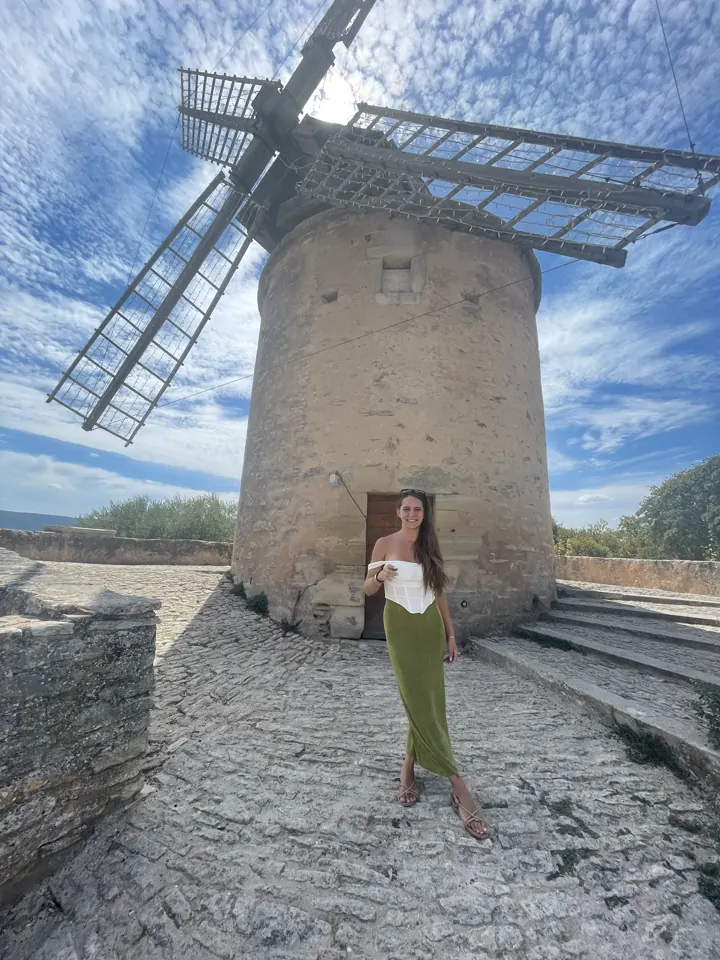 A woman standing in front of a stone windmill