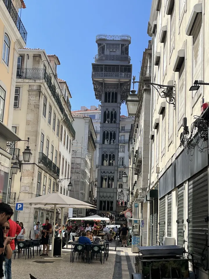 A city street lined with buildings leading to the iron Santa Justa Lift