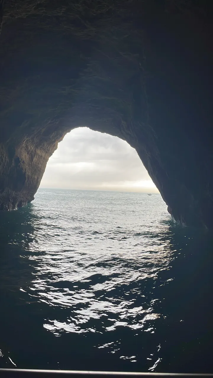 Looking out of a dark sea cave through an arch to the sea