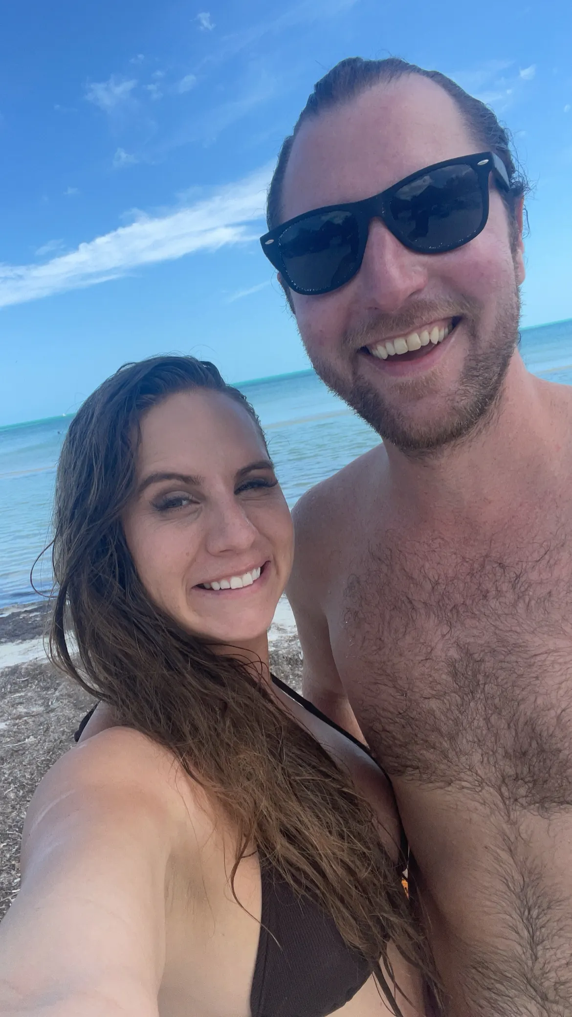 A couple taking a selfie on a white-sand beach on Holbox