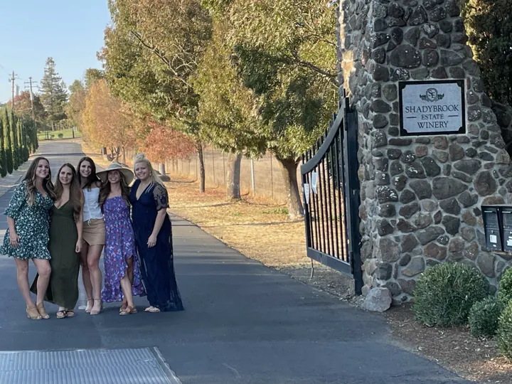A group of women posing by a stone winery entrance