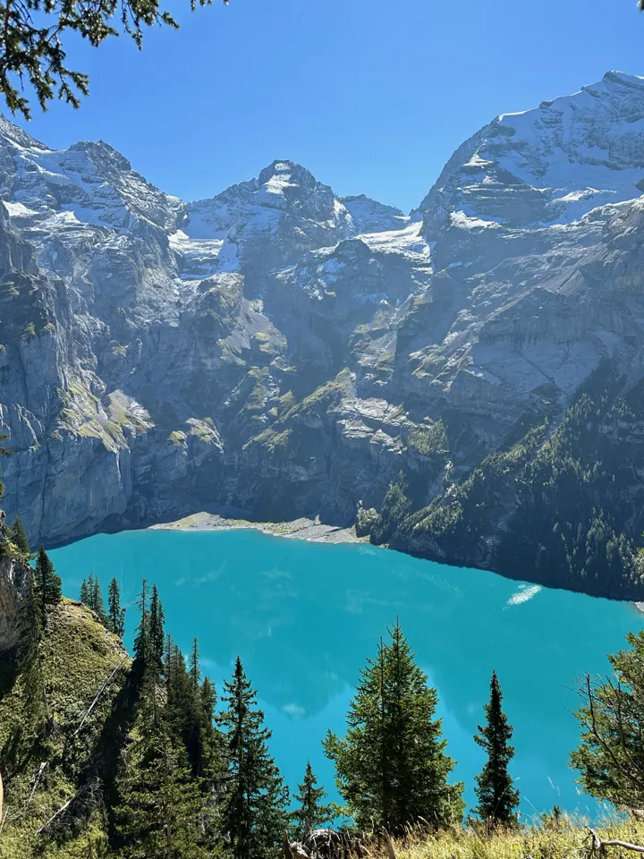Turquoise lake surrounded by steep mountains seen from above