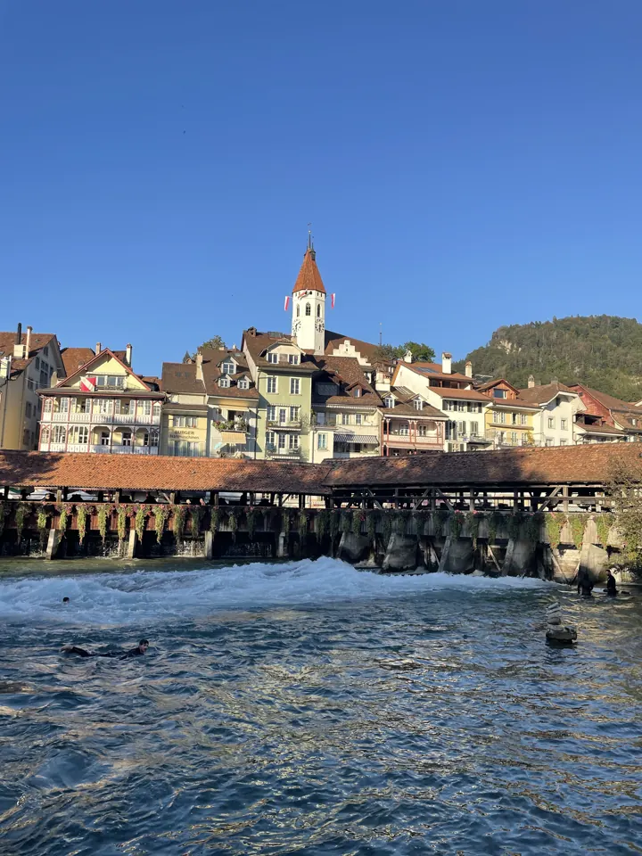 Thun's old town buildings and church tower above the rushing river