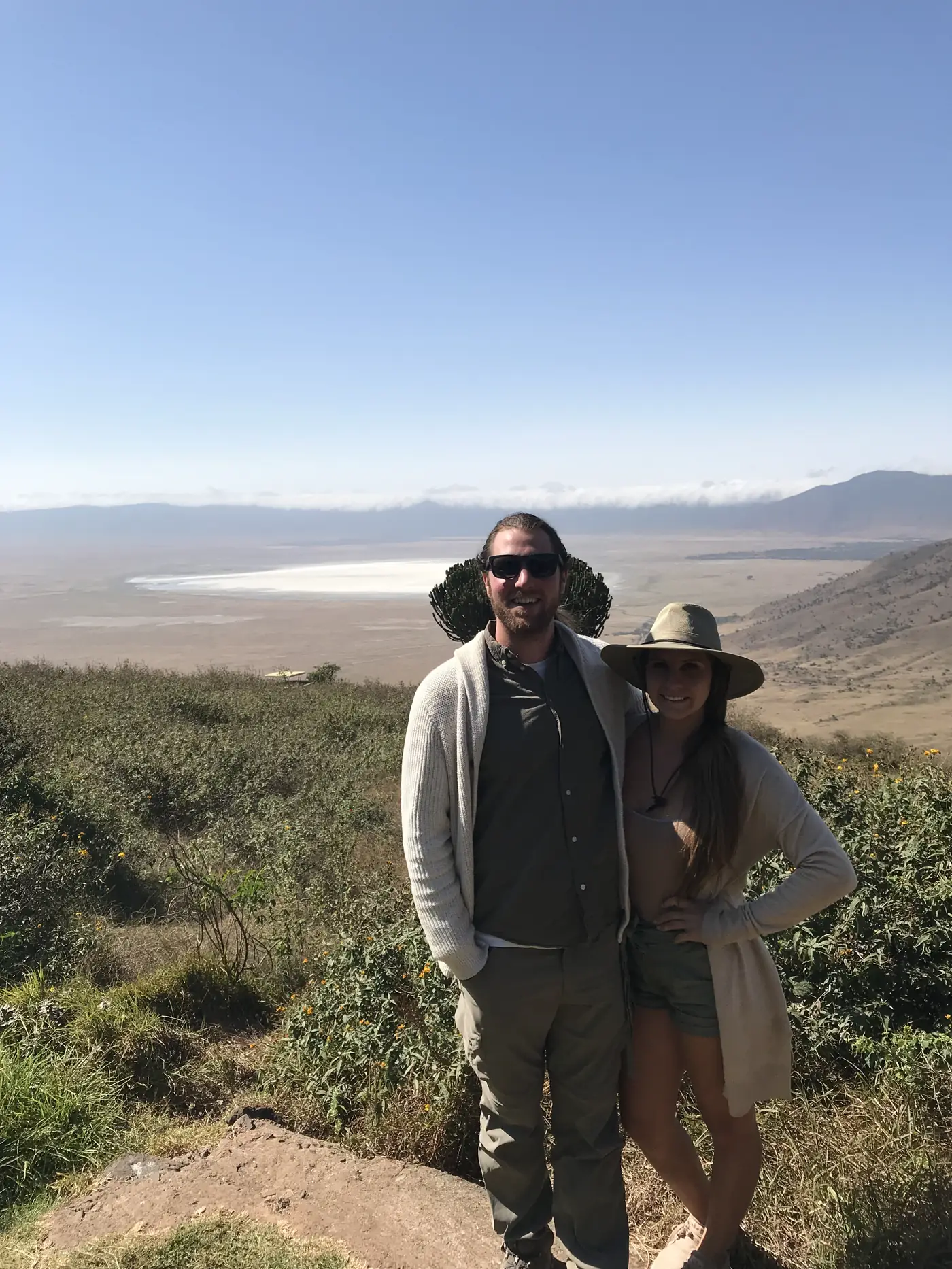 A couple standing on the crater rim with the crater floor and lake below