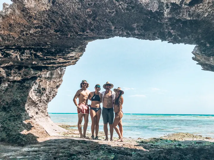 Four family members standing inside a rock arch overlooking the sea