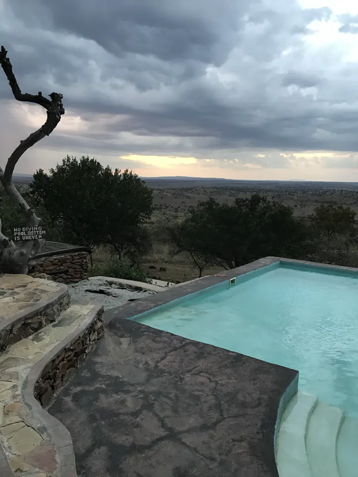 A rock-lined plunge pool at a lodge under dramatic grey clouds