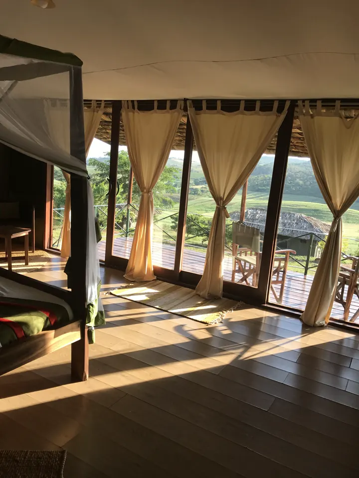 A lodge room with a canopy bed and curtained glass walls opening to a deck