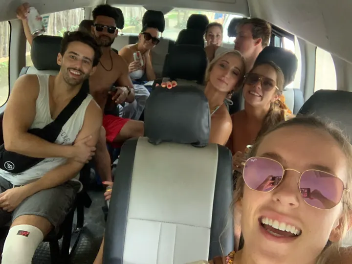 A group of smiling friends packed into a van on a road trip