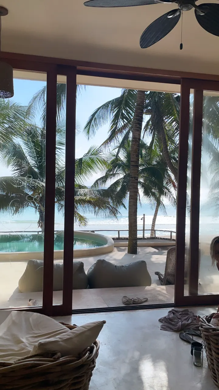 A villa living room opening through glass doors to a pool and palm trees