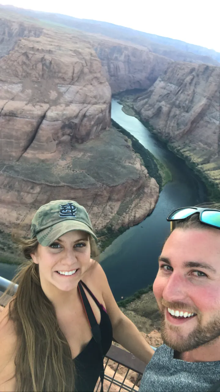 A couple taking a selfie with Horseshoe Bend behind them