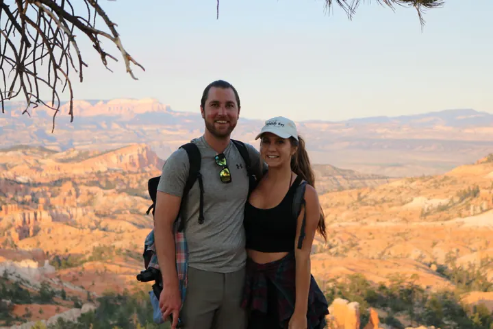 A couple posing at an overlook above an orange canyon at golden hour