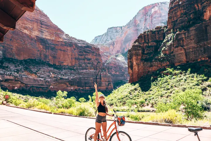 A person biking the scenic canyon road beneath red cliffs