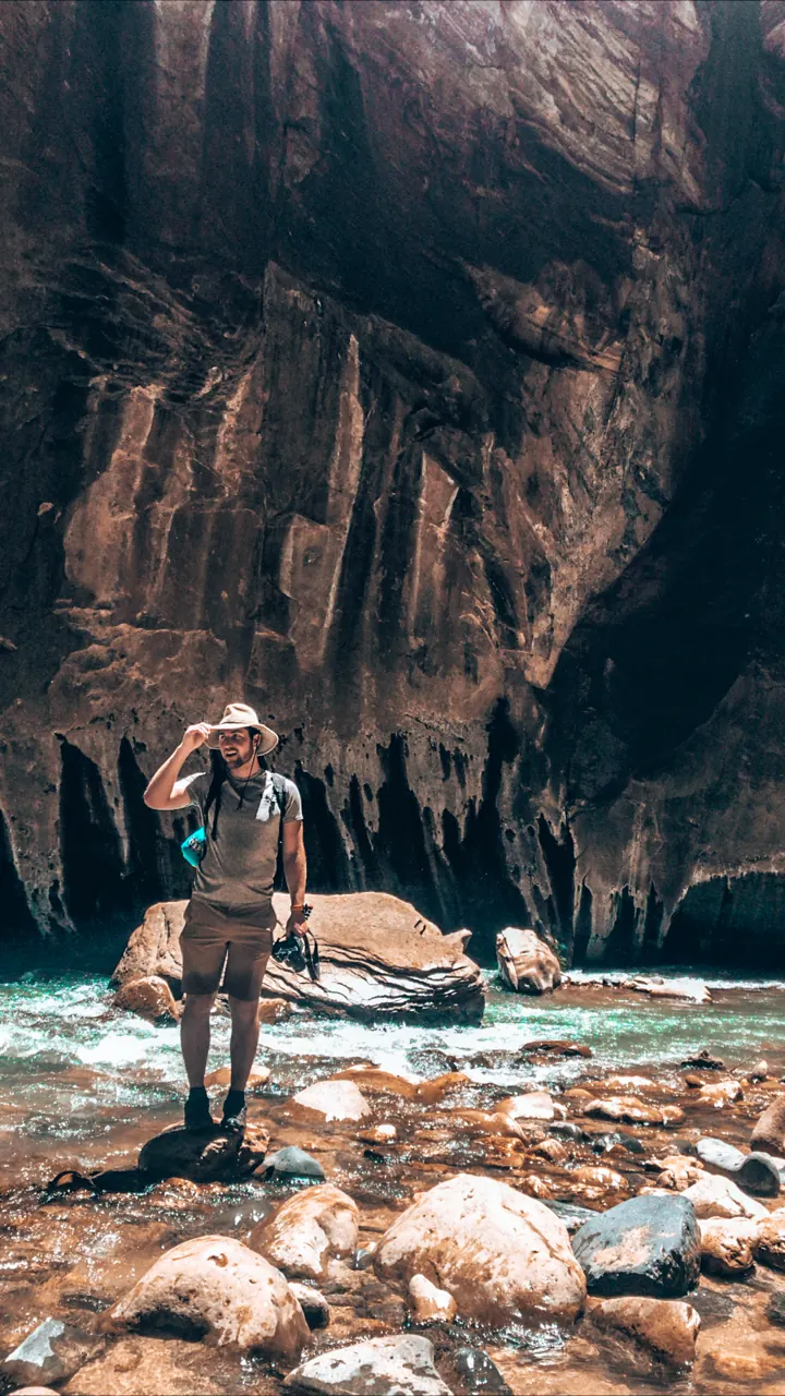 A hiker standing in the river surrounded by sheer canyon walls